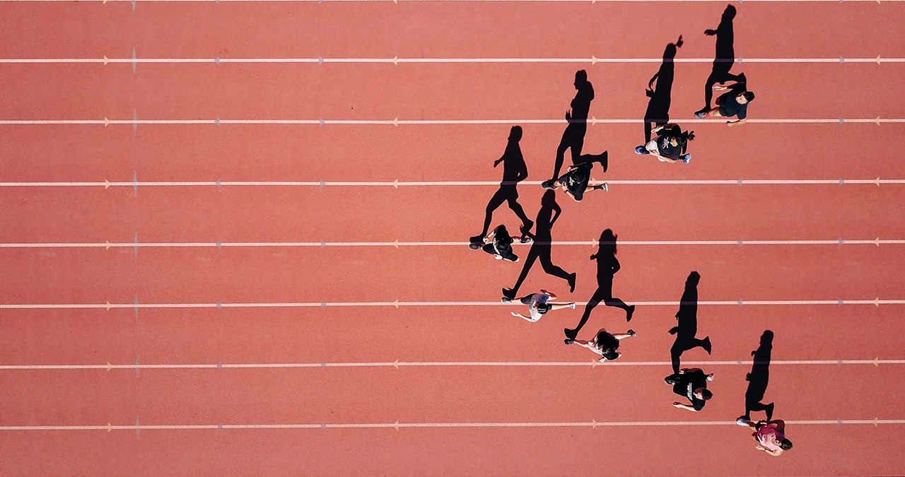 An overhead shot of people running on a red running track